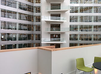 Modern office atrium with glass facade and green chairs