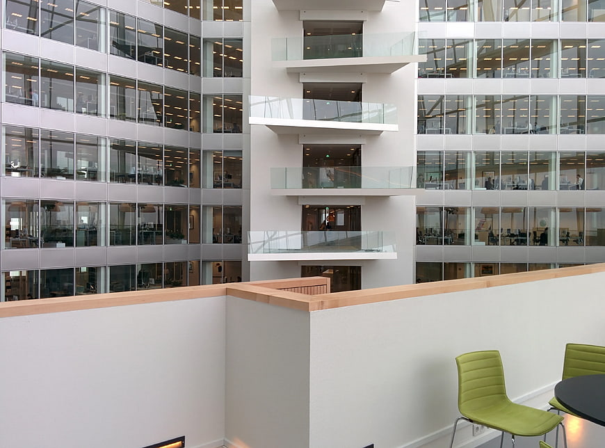 Modern office atrium with glass facade and green chairs