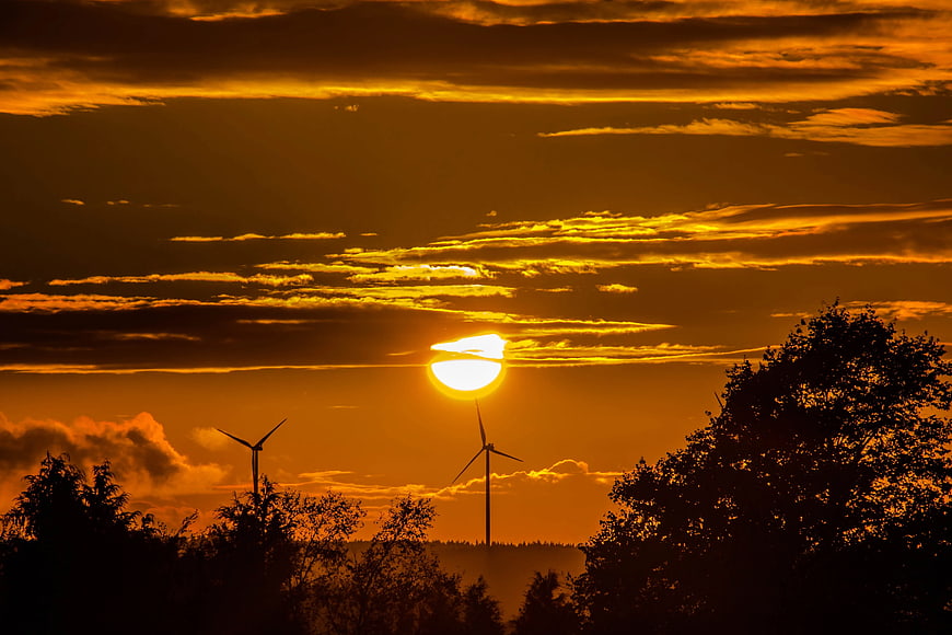 Silhouetted Wind Turbines Against Golden Sunset Sky