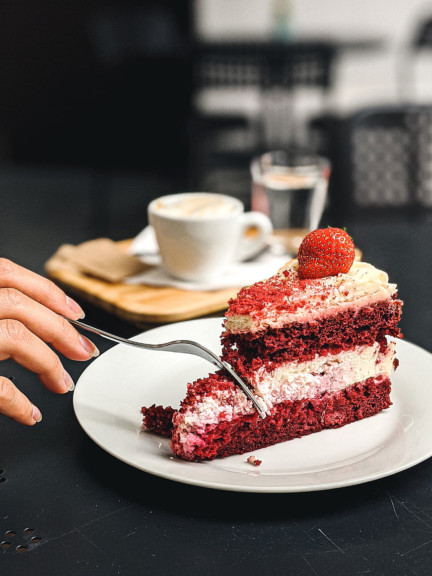 Slice of red velvet cake with strawberry and coffee