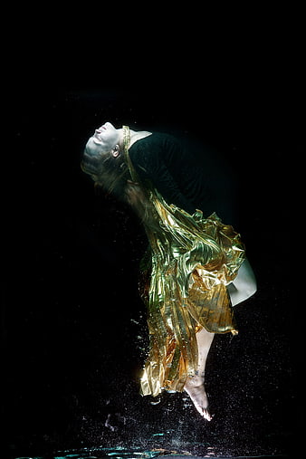 Underwater fashion photography of woman in golden metallic fabric