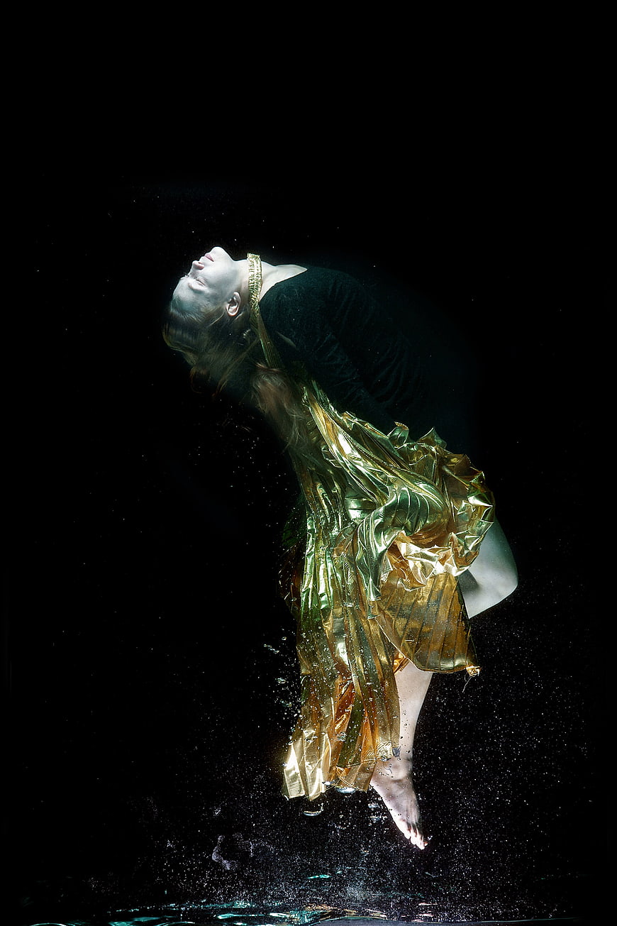 Underwater fashion photography of woman in golden metallic fabric