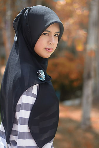 Portrait of young woman wearing black hijab and striped shirt outdoors