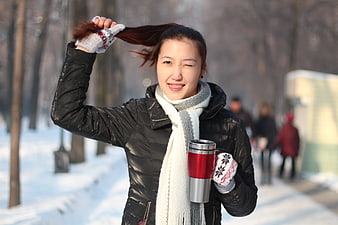 Happy Woman Winking with Travel Mug in Snowy Park