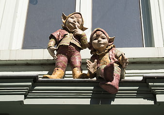 Weathered wooden elf figurines sitting on a building ledge