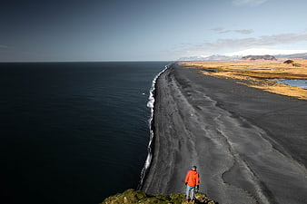 Man overlooking black sand beach and ocean coastline