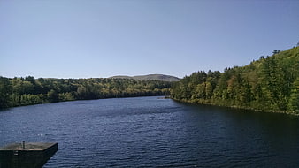 Serene River Landscape with Forested Hills and Blue Sky