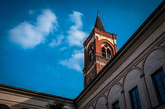 Low angle view of historic brick church tower against blue sky