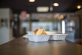 Takeout food in white container on counter with bokeh background
