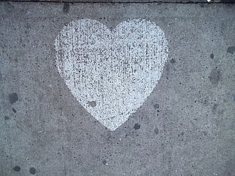 White chalk heart drawing on gray concrete sidewalk pavement