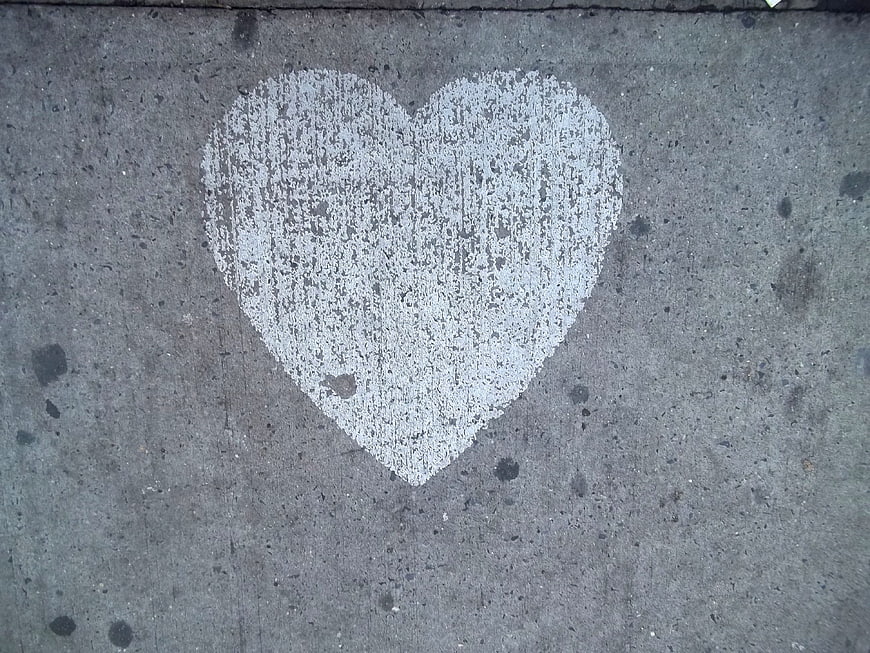 White chalk heart drawing on gray concrete sidewalk pavement