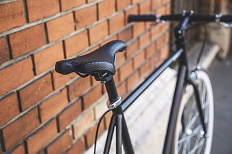 Black bicycle seat against red brick wall