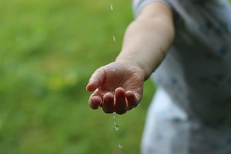 Child's Hand Catching Raindrops in Nature