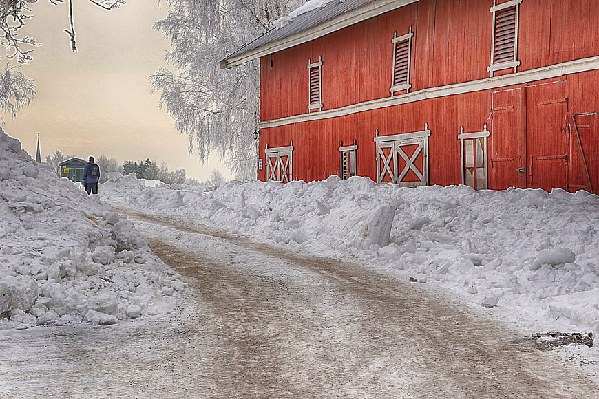 Red Barn on Snowy Winter Road with Person Walking