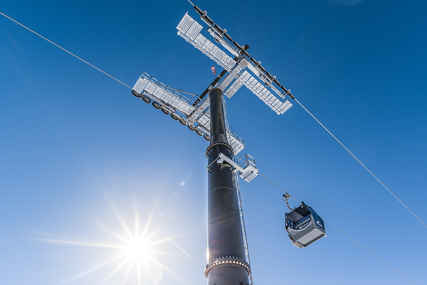 Low angle view of ski gondola lift tower against blue sky