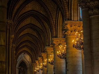 Gothic Cathedral Interior with Lit Chandeliers and Stone Pillars