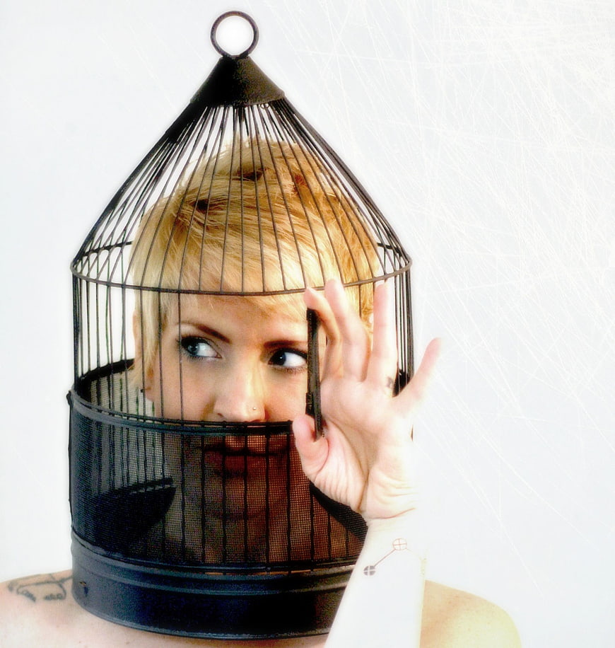 Woman with birdcage on head conceptual portrait