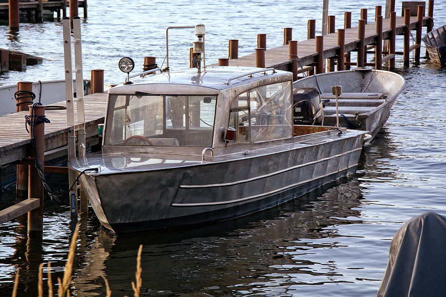 Silver aluminum motorboat docked at wooden pier