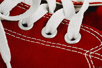 Close-up of red canvas shoe with white laces and stitching
