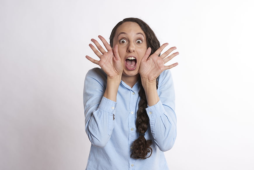 Surprised young woman screaming with hands near face