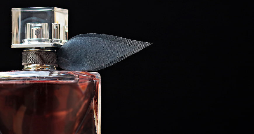 Luxury perfume bottle with black ribbon on black background