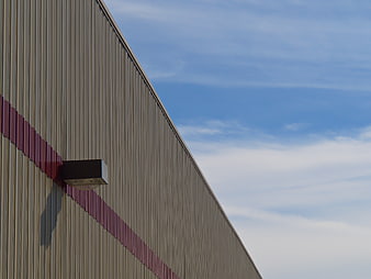 Modern industrial building facade with corrugated metal and blue sky