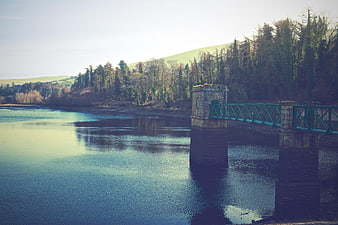 Historic Stone Bridge Over Calm Water With Forest Reflections