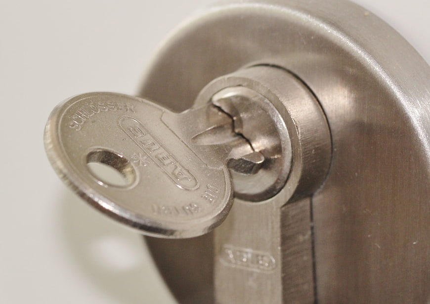 Close-up of a metal key inserted into a door lock cylinder