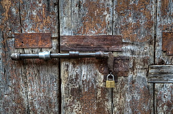 Rusty padlock on weathered wooden door with iron latch