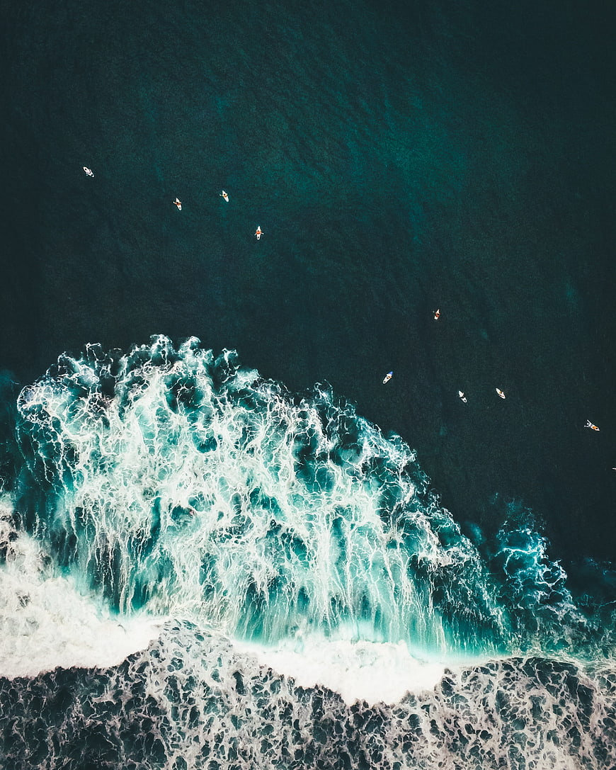 Aerial view of surfers waiting for waves in deep blue ocean