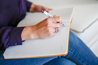 Woman writing in notebook with pen on lap