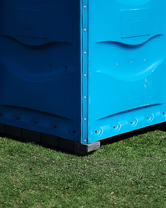 Close-up of blue portable toilet on green grass