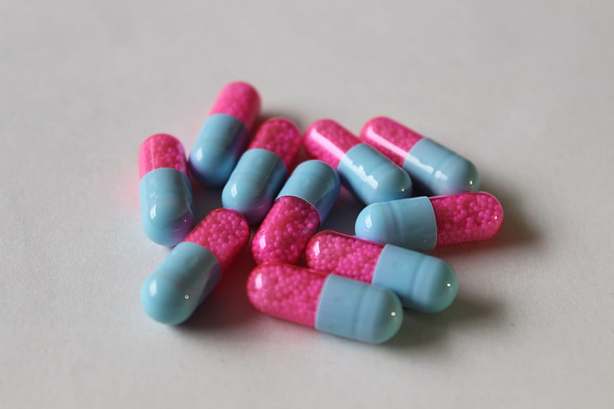 Pink and Blue Gel Capsules on White Surface