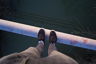 First-person view of feet on a pipe over water