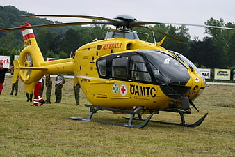 Yellow ÖAMTC rescue helicopter on grass field