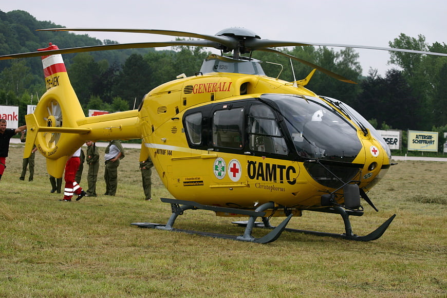 Yellow ÖAMTC rescue helicopter on grass field