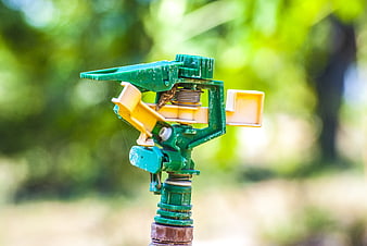 Close-up of green garden sprinkler head in outdoor setting