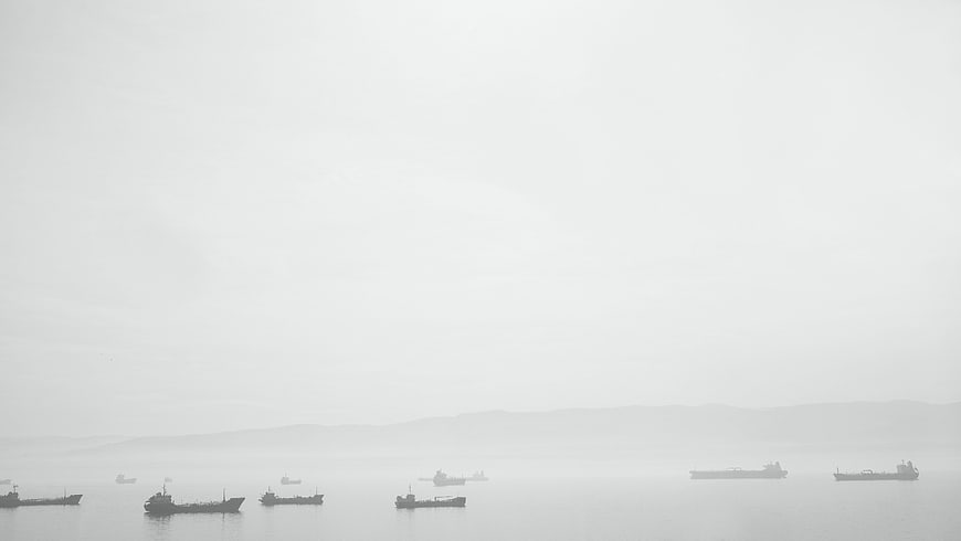 Silhouettes of cargo ships in foggy harbor