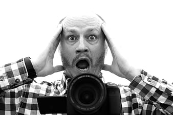 Bald Man With Shocked Expression Holding Camera