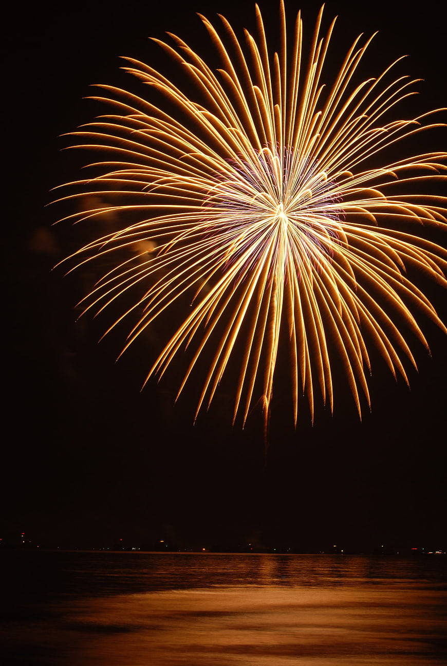 Golden Fireworks Bursting Over Dark Sea At Night