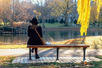 Woman in Black Coat Sitting on Park Bench in Autumn