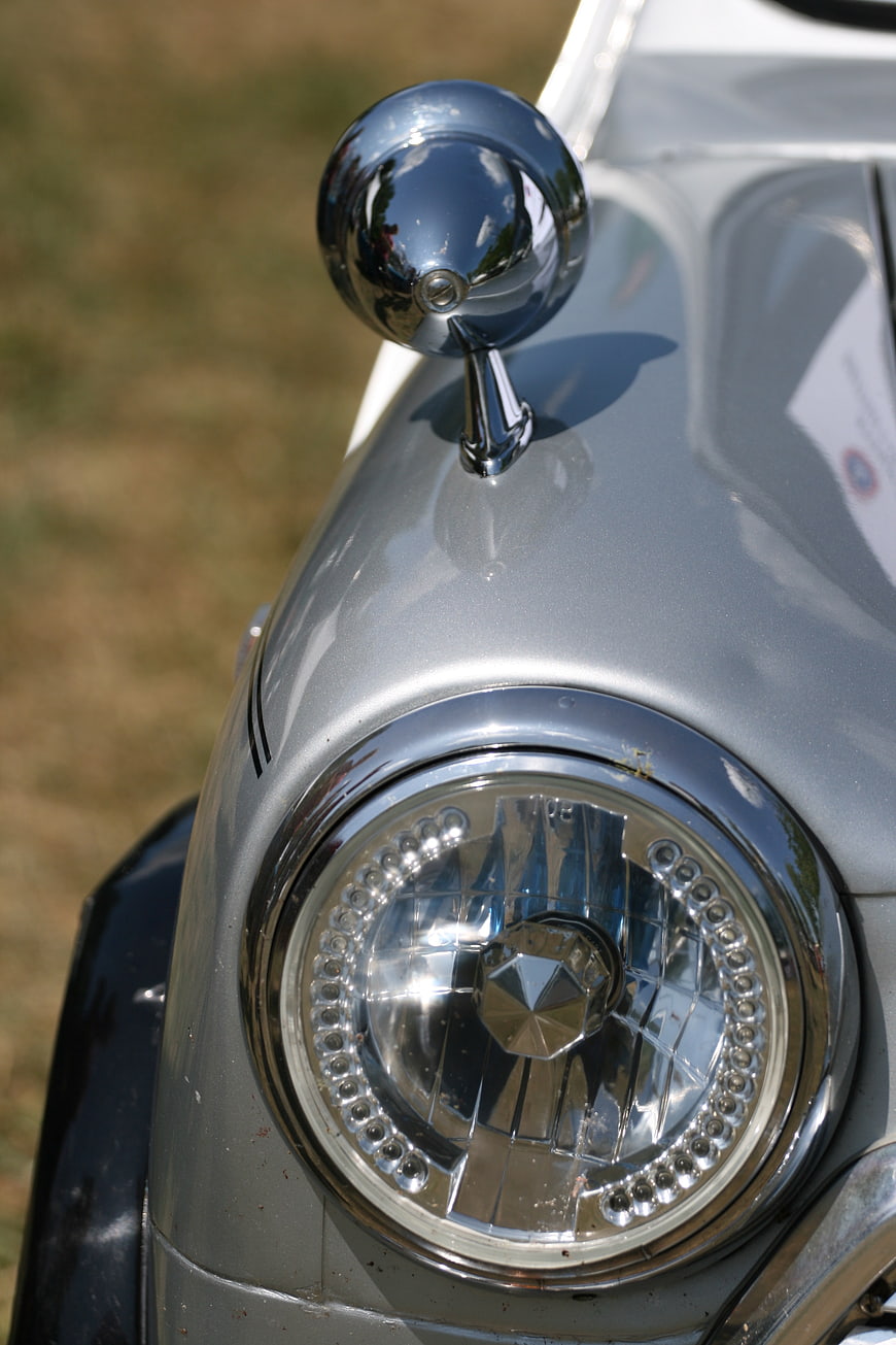 Close-up of vintage silver car headlight and chrome mirror