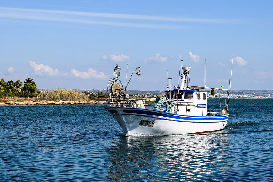 White and blue fishing boat sailing on calm sea