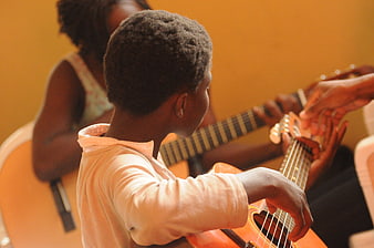 African child learning to play acoustic guitar in a music class