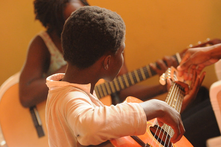 African child learning to play acoustic guitar in a music class