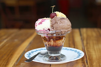 Delicious Ice Cream Sundae with Chocolate and Cherry on Wooden Table