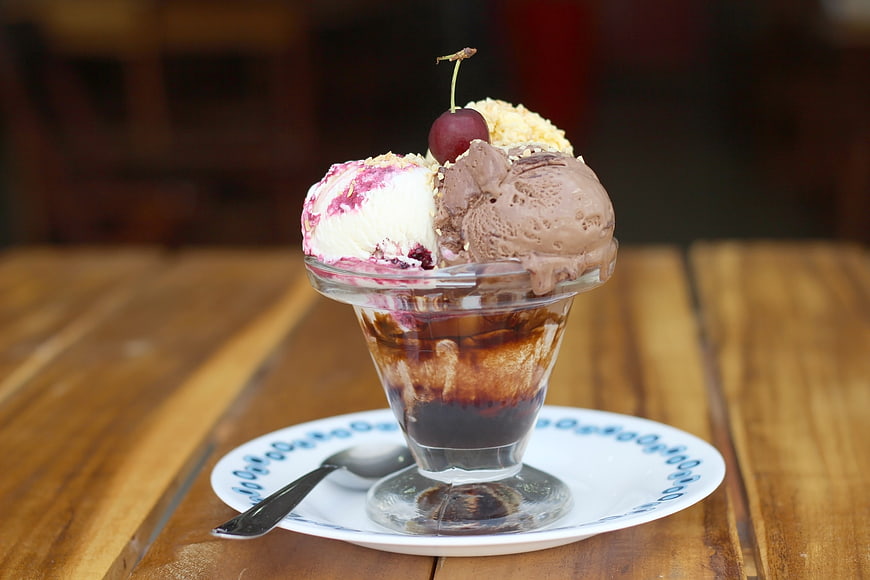 Delicious Ice Cream Sundae with Chocolate and Cherry on Wooden Table