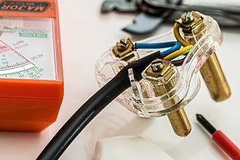 Close-up of electrical plug wiring and multimeter for DIY repair