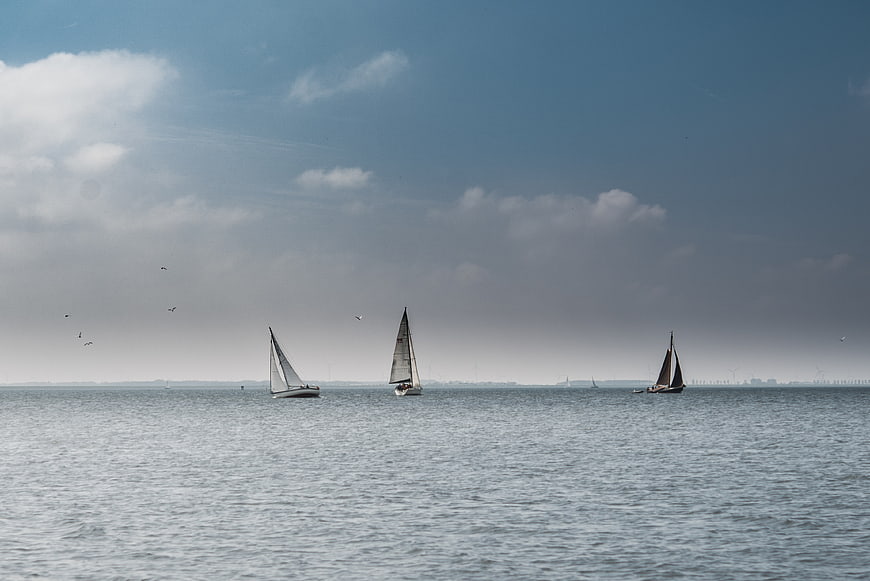 Sailboats on calm sea with blue sky and clouds