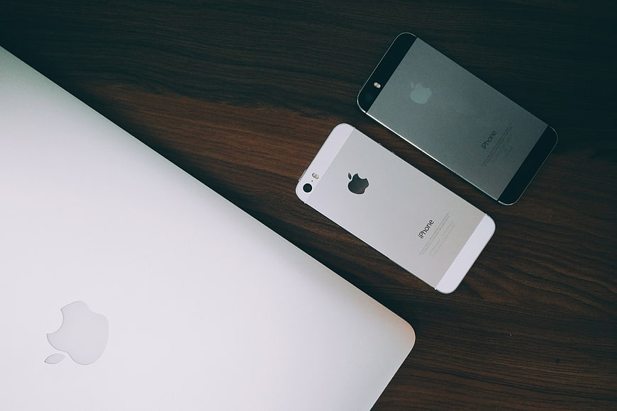 Apple MacBook and iPhones on Dark Wood Desk